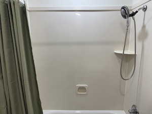 Bathroom view of shower / bath combo with shower curtain