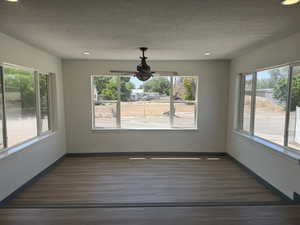 Unfurnished dining area featuring wood finished floors, a textured ceiling, recessed lighting, a ceiling fan, and baseboards
