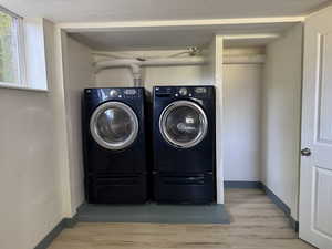 Laundry room with independent washer and dryer, wood finished floors, and baseboards