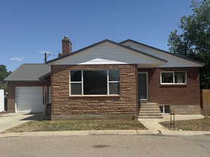 View of front facade with an attached garage, entry steps, concrete driveway, and a chimney