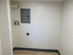 Washroom featuring electric panel, wood finished floors, hookup for a washing machine, hookup for an electric dryer, and baseboards