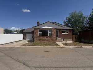 View of front facade with concrete driveway, a chimney, and a garage