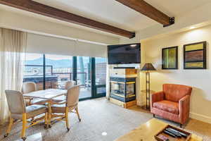 Dining area featuring a multi sided fireplace, beamed ceiling, and baseboards