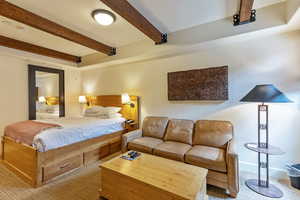 Bedroom featuring carpet and beamed ceiling