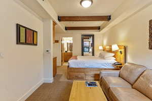 Bedroom with light carpet, beam ceiling, and baseboards