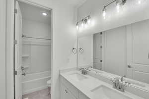 Full bathroom featuring double vanity, toilet, and washtub / shower combination