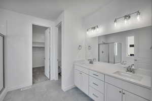 Full bath with a shower stall, toilet, double vanity, a spacious closet, and tile patterned flooring