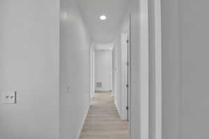 Hall with baseboards, light wood finished floors, and recessed lighting