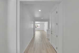 Corridor with light wood-type flooring, recessed lighting, and baseboards