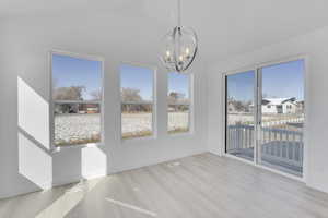 Unfurnished dining area featuring a chandelier, wood finished floors, baseboards, and high vaulted ceiling