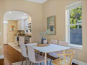 Dining area featuring arched walkways, baseboards, wood finished floors, and recessed lighting