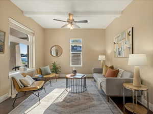 Living area with baseboards, beam ceiling, ceiling fan, and wood finished floors