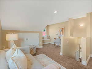 Carpeted living room featuring baseboards and vaulted ceiling