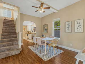 Dining space featuring wood finished floors, arched walkways, a ceiling fan, stairs, and baseboards