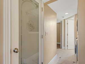 Hallway with light marble finish flooring, baseboards, and washer / clothes dryer