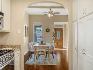 Dining space featuring arched walkways, a ceiling fan, dark wood-type flooring, and baseboards