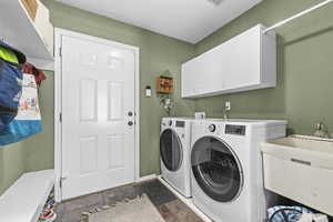 Washroom with separate washer and dryer, cabinet space, dark stone finish floors, and baseboards
