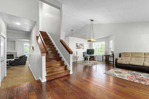 Staircase featuring hardwood / wood-style flooring, a tile fireplace, high vaulted ceiling, baseboards, and recessed lighting