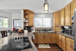 Kitchen featuring stainless steel microwave, black electric stovetop, a sink, and backsplash