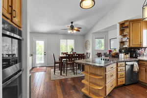 Kitchen featuring open shelves, stainless steel appliances, a peninsula, vaulted ceiling, and dark wood-type flooring