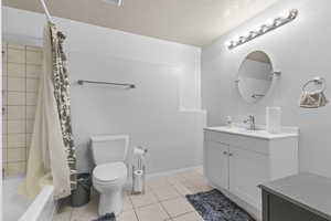 Full bath with vanity, shower / bath combo, toilet, and tile patterned floors