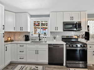 Kitchen with stainless steel appliances, a sink, healthy amount of natural light, and white cabinets