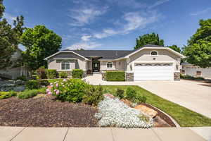 Ranch-style house with stone siding, stucco siding, a garage, and driveway