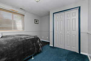 Bedroom with carpet, a closet, a textured ceiling, and baseboards