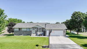 Ranch-style house with a garage, concrete driveway, and a front lawn