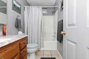 Bathroom with vanity, toilet, shower / bathtub combination with curtain, and tile patterned flooring
