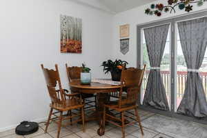 Dining room featuring light tile patterned floors, vaulted ceiling, and baseboards