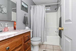 Full bathroom featuring toilet, vanity, shower / bath combo, and tile patterned floors