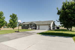 Ranch-style house featuring a garage, a front yard, and concrete driveway