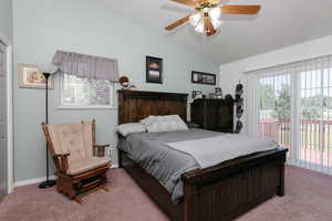 Bedroom featuring access to exterior, vaulted ceiling, light carpet, and ceiling fan