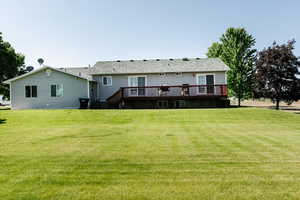 Back of house with a deck and a lawn