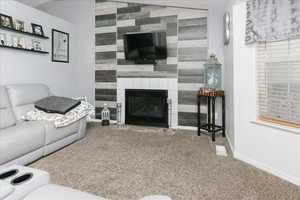 Living area featuring an accent wall, carpet floors, baseboards, and a large fireplace