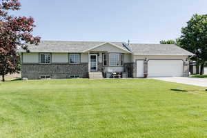Ranch-style home featuring a garage, a front lawn, concrete driveway, and stucco siding