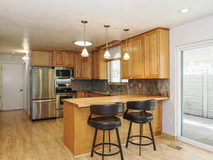 Kitchen featuring appliances with stainless steel finishes, wooden counters, a sink, and light wood-style flooring