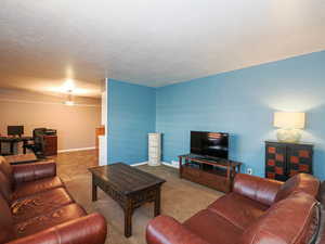 Living room featuring an office area, carpet flooring, baseboards, and a textured ceiling
