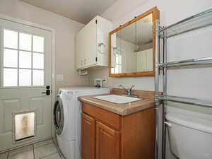Laundry area featuring a sink, light tile patterned flooring, and washer and dryer