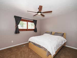 Bedroom featuring baseboards, a textured ceiling, carpet, and a ceiling fan