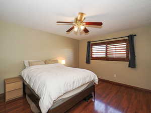 Bedroom with wood finished floors, baseboards, a textured ceiling, and a ceiling fan