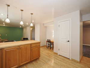 Kitchen featuring butcher block countertops, decorative light fixtures, light wood-style flooring, baseboards, and recessed lighting