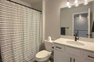 Bathroom with toilet, vanity, and a shower with curtain