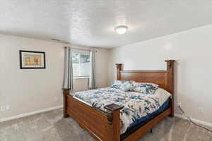 Carpeted bedroom with a textured ceiling and baseboards