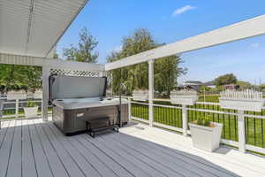 Deck featuring a hot tub and a lawn