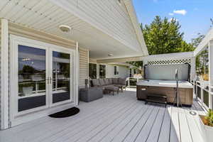 Wooden terrace with a hot tub, french doors, and an outdoor hangout area