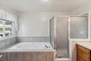 Full bathroom with a whirlpool tub, a shower stall, and vanity