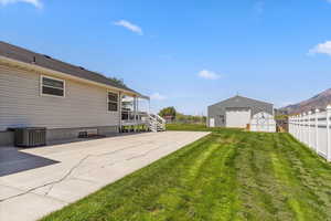 View of yard with central AC, a detached garage, an outbuilding, and driveway