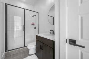 Bathroom featuring vanity, a shower stall, toilet, and tile patterned flooring